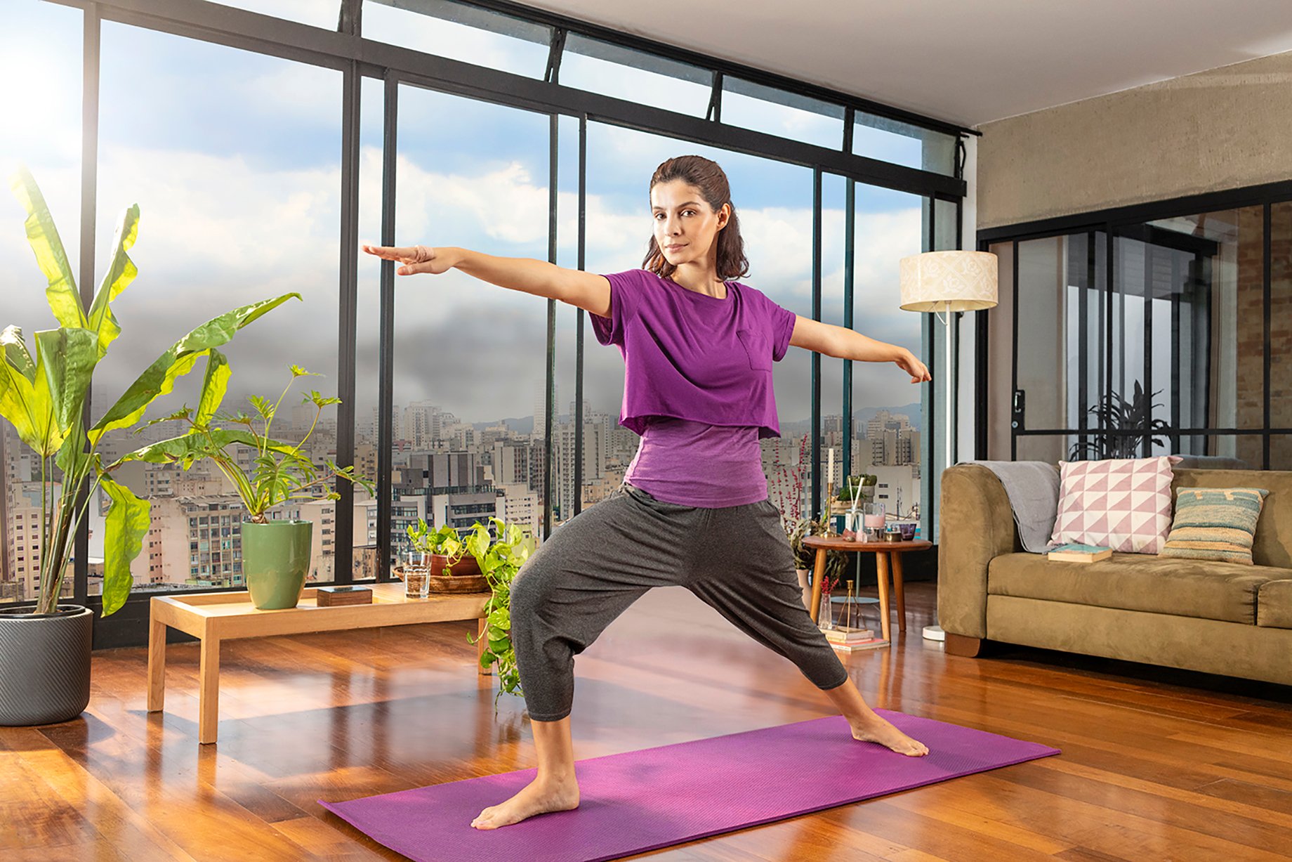 Woman practicing yoga in apartment with large windows with a view of Sao Paulo shot by Claus Lehmann for Allegra