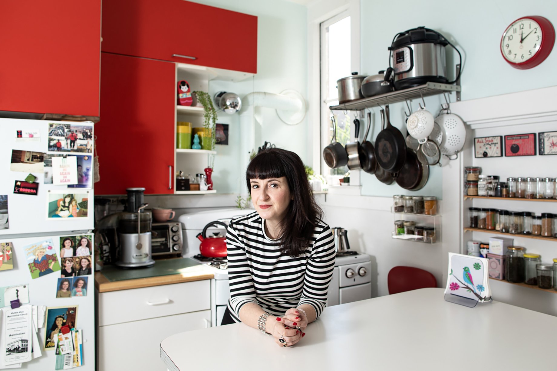 Woman in an organized kitchen with bright red cabinets shot by Jaime Borschuk for Women at Home project
