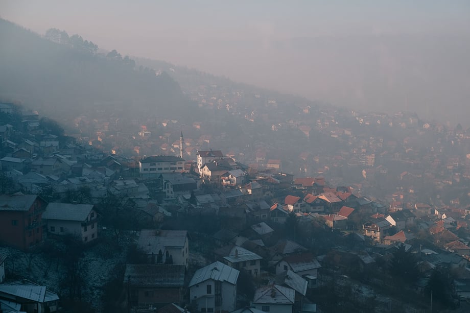 A neighborhood in the hills above Sarajevo on a heavily polluted day. Individual households stretch into the hills on either side of the city, where many lower income families live and rely on poor quality fuels burned in stoves or fireplaces for heating. Photography by Nick St. Oegger. 
