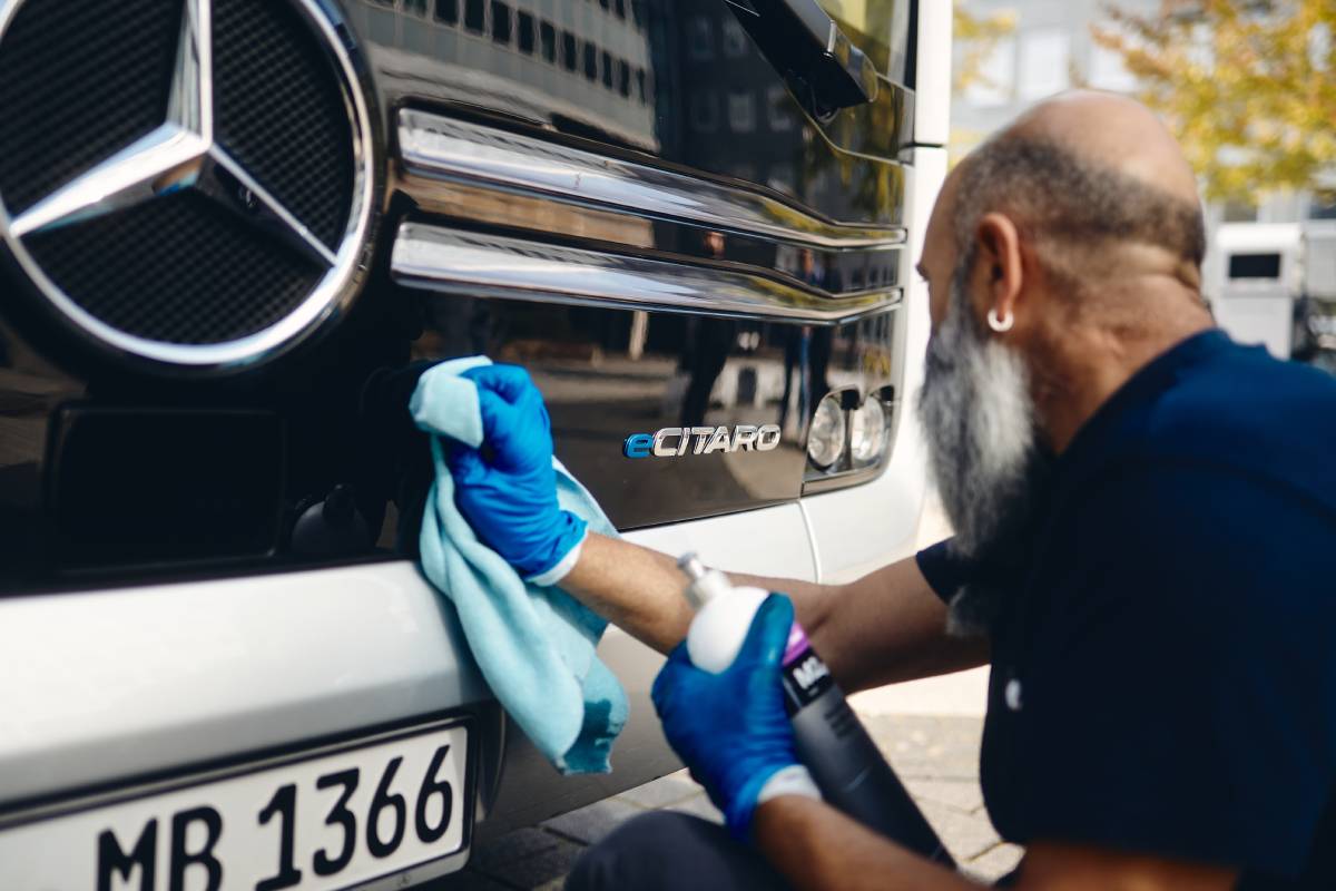 Photo of a man polishing the front of an electric bus.