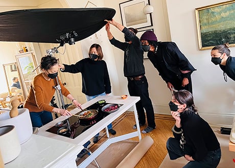 Talent and crew with photographer Emily Andrews setting up for an overhead cooking shot during photoshoot for New York City energy provider Con Edison.