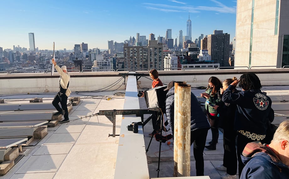 Photographer Emily Andrews and crew facing the sun on Con Edison's rooftop with iconic New York City buildings behind.