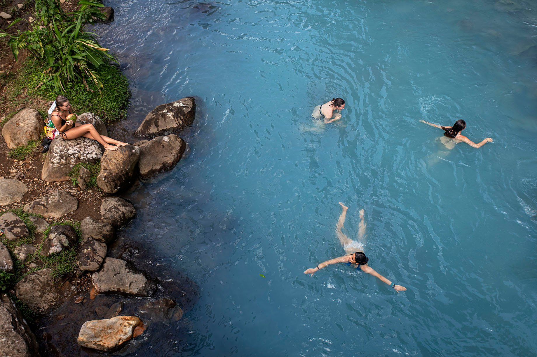 Three women swimming by waterfall in Parque Nacional del Volcan Tenorio shot by Cristina Candel for Viajar magazine