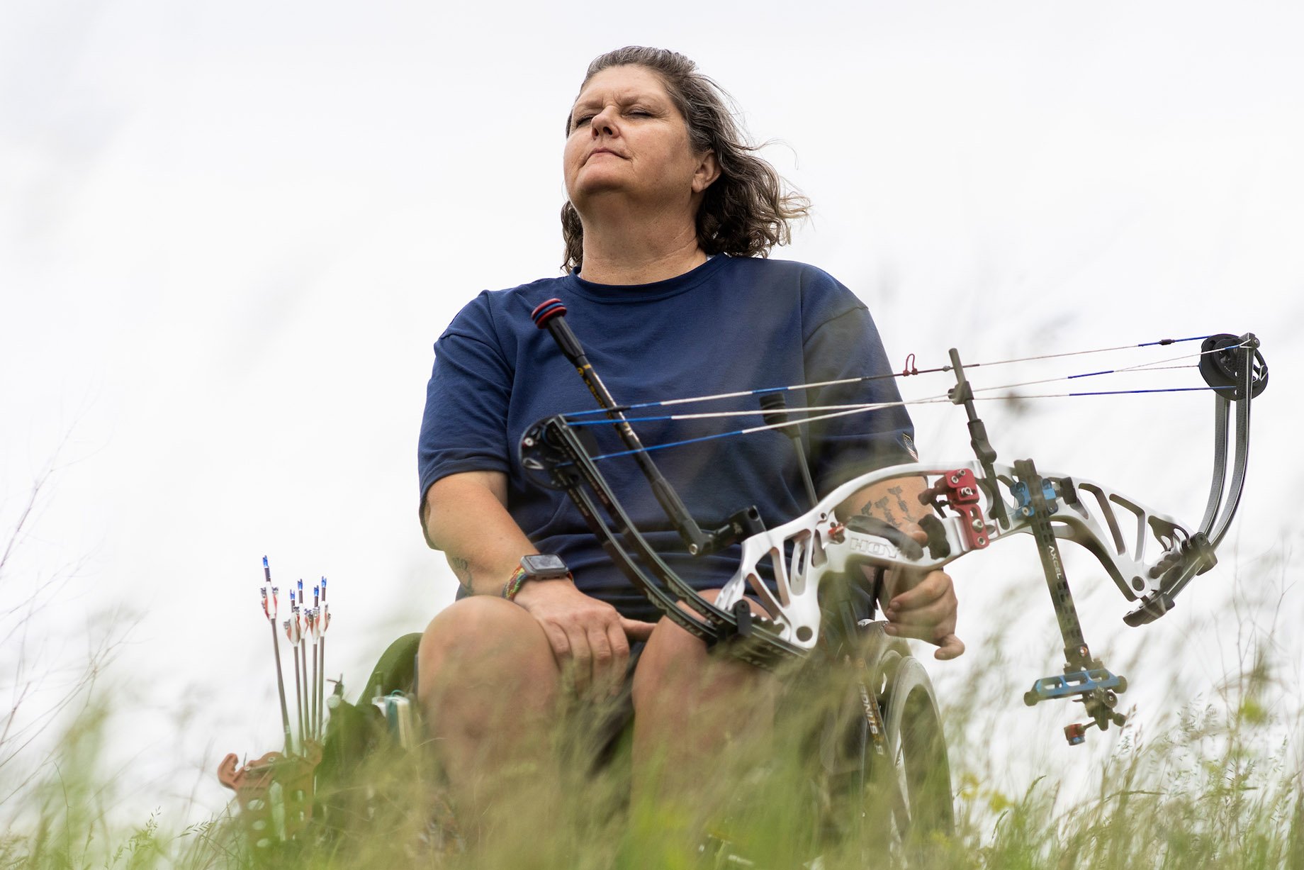 Lia Coryell holding archery arrow in field shot by Lauren Justice for the New York Times