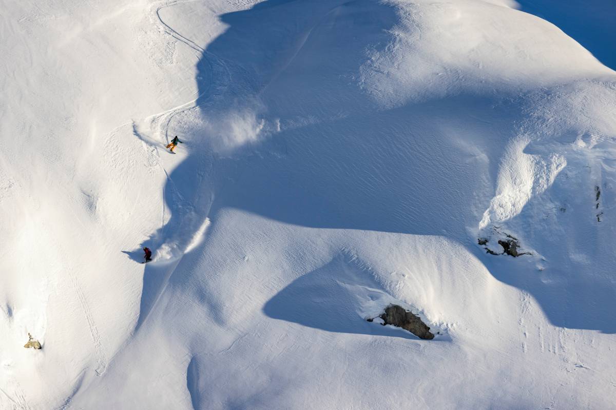 High-up photo of a snowboarders winding down a steep hill captured by Ben Girardi.