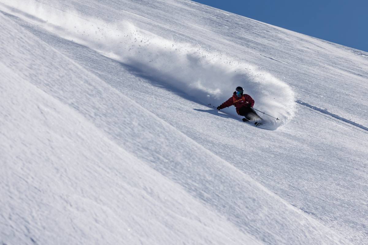 Action photo of a skier speeding down a steep hill.