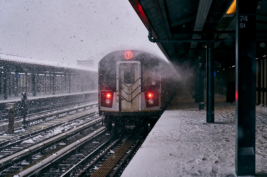From Shravya Kag's photo essay The International Express, image of the 7 subway train in New York City stopping at a snowy and empty 74th St elevated and outdoor stop.