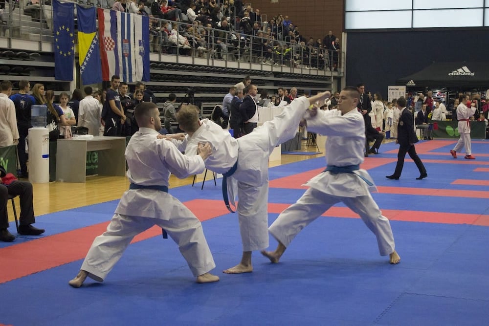 Image of karate champion Mihael Ećimović demonstrating a defense maneuver against two opponents.