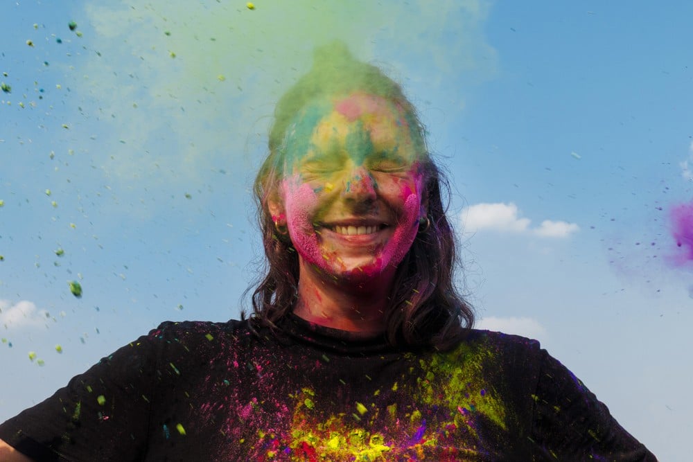 Image of smiling figure with a cloud of colorful dust around head, by Mumbai-based portrait photographer Parikshit Rao.