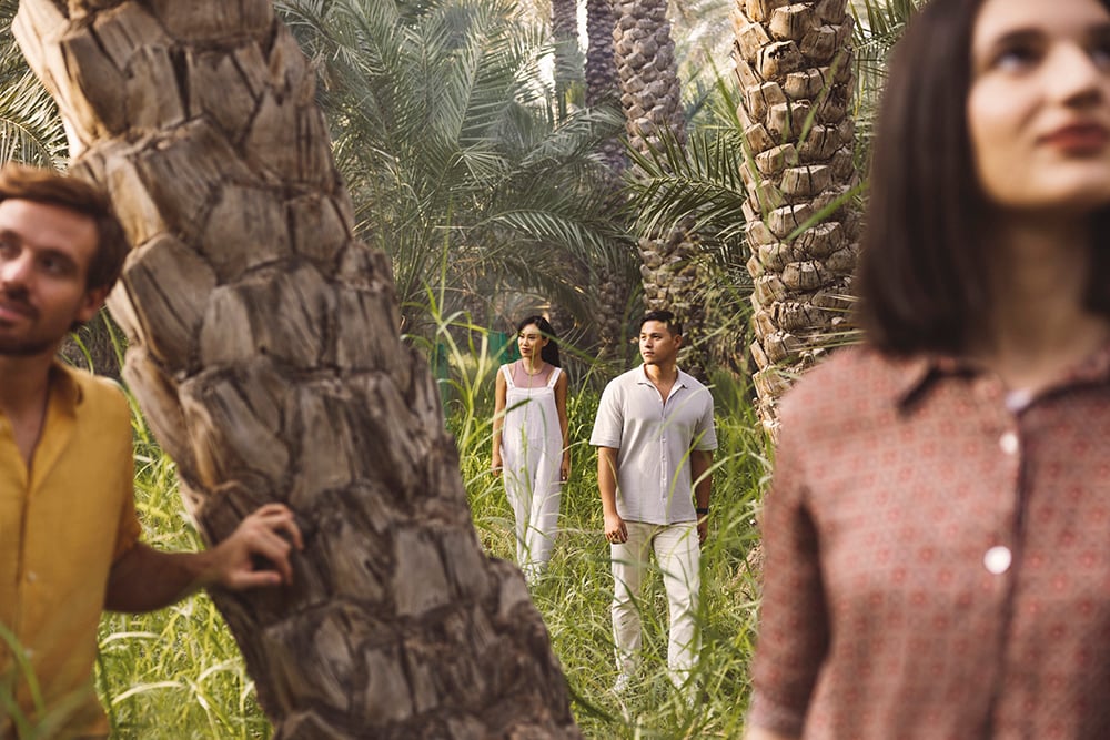 A group of adults wander in a natural park with palm trees for Experience Abu Dhabi Campaign.