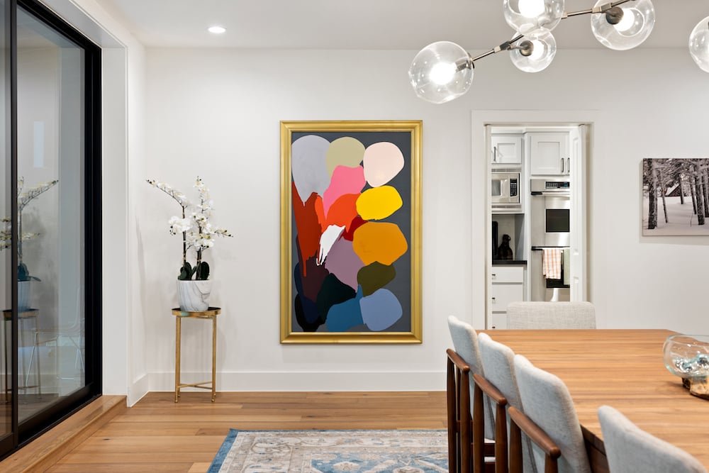 Image of artist's colorful painting hanging framed on a wall of private residence, by Austin-based lifestyle photographer Nick Barnes.