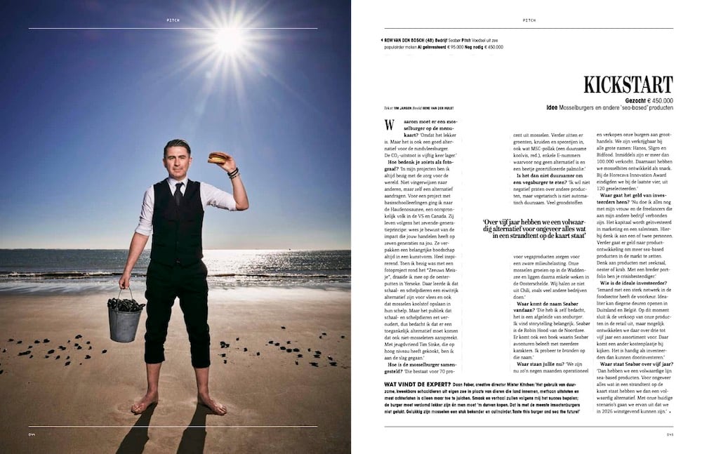 Tear sheet of seafood entrepreneur in white dress shirt and black vest and pants standing on beach with mussels and mussel burger on sunny day, by Tilburg, Netherlands-based portrait photographer René van der Hulst.