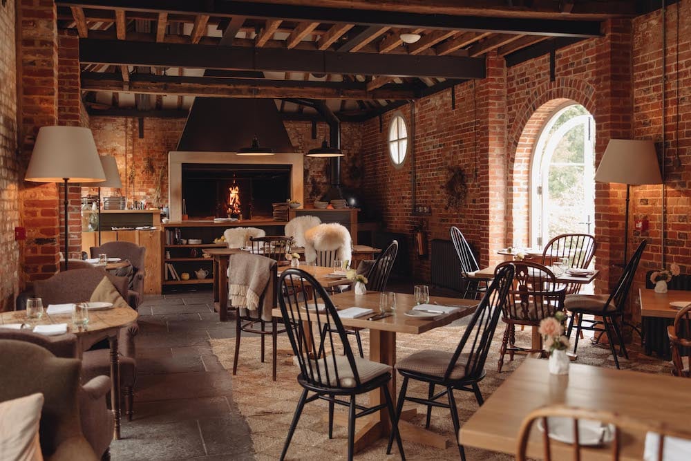 Image of cosy restaurant interior with open hearth, exposed bricks and wooden beams, by London-based portrait photographer Dunja Opalko.