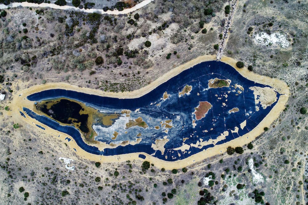 Aerial photo of a deep blue abandoned reservoir, surrounded by sand and trees, by Donostia-San Sebastian, Spain-based social documentary photographer Markel Redondo. 