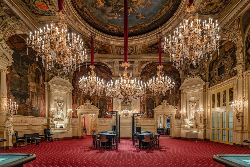 Photo of red and cream interior of great hall and gambling tables, with crystal chandeliers, by Baden-Baden, Germany-based architecture photographer Torben Beeg.