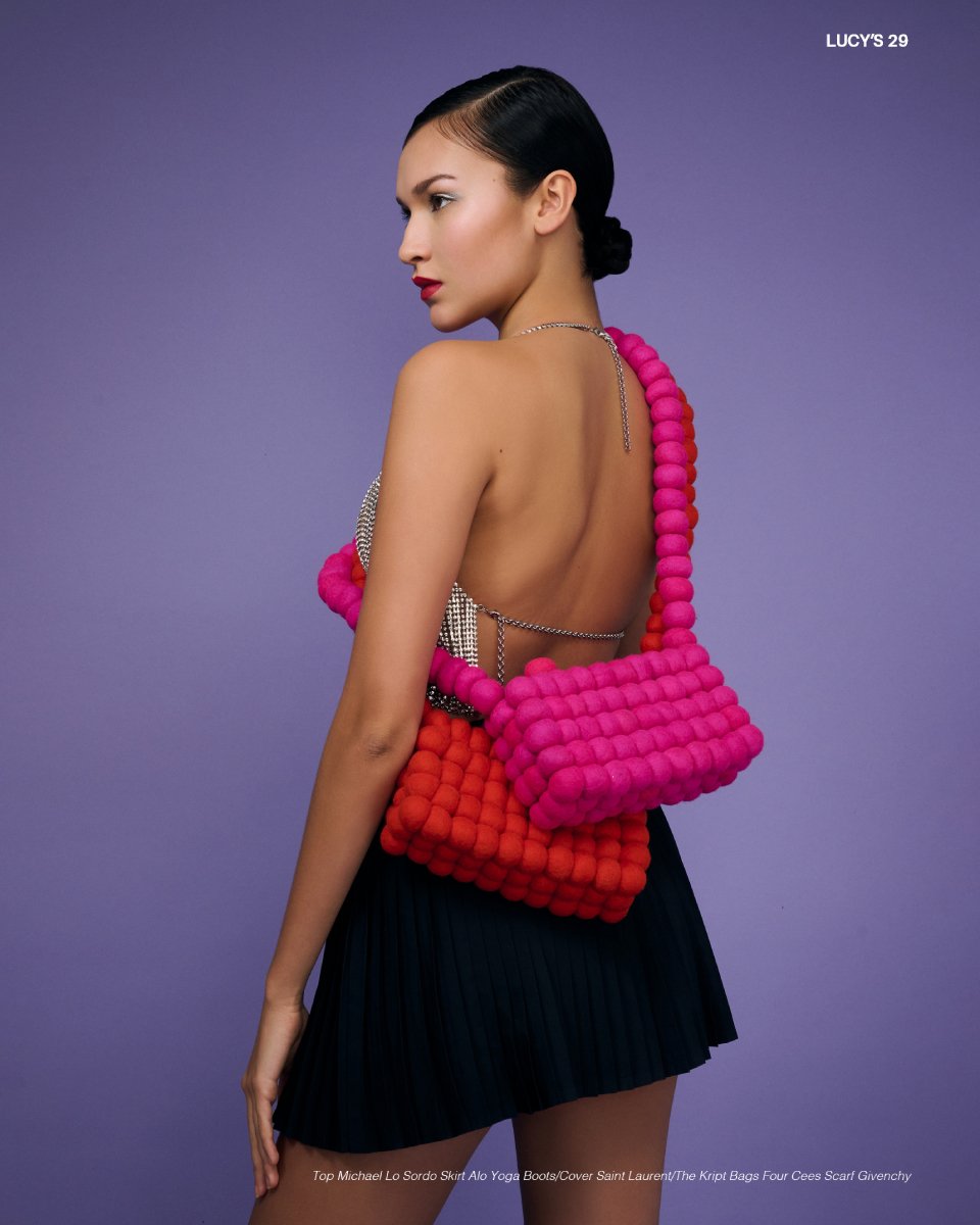 Photo by Matthew Mills of a model from behind wearing two handbags.