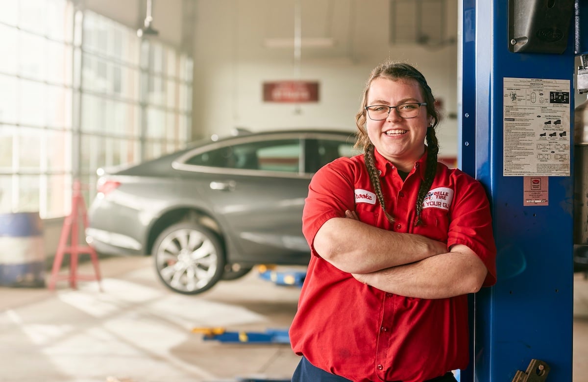 Portrait of Belle Tire employee in red uniform, posing in mechanic's shop, by Chicago-based brand narrative photographer Nathanael Filbert.