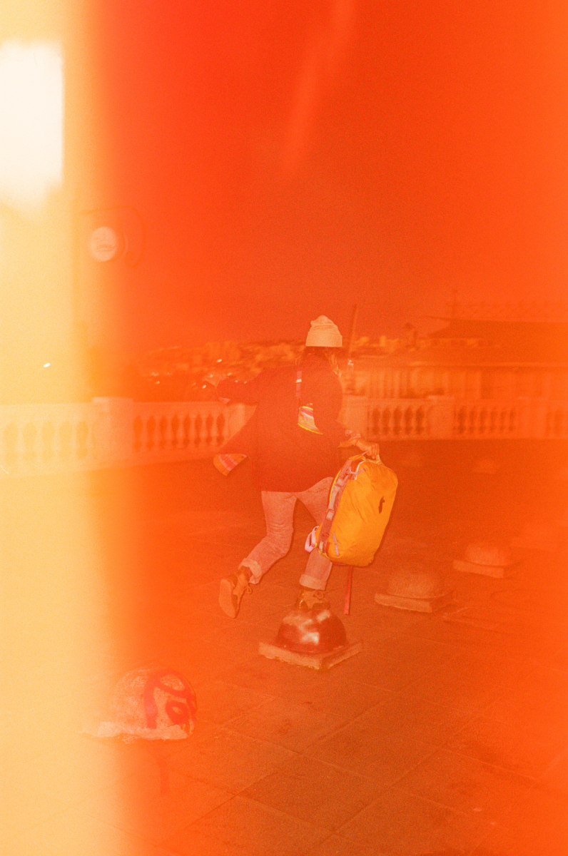 A washed out analog color photo by Adam Wells of a model with a Cotopaxi backpack.