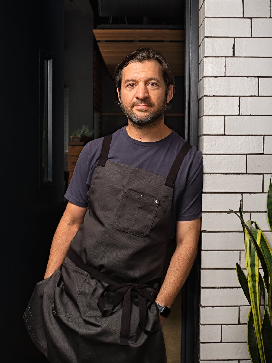 Photo of a Detroit chef leaning on the wall of his restaurant. 
