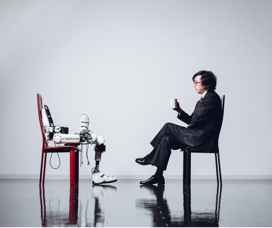 Portrait of man and robot facing each other, sitting in chairs by Tokyo, Japan-based photographer Irwin Wong.