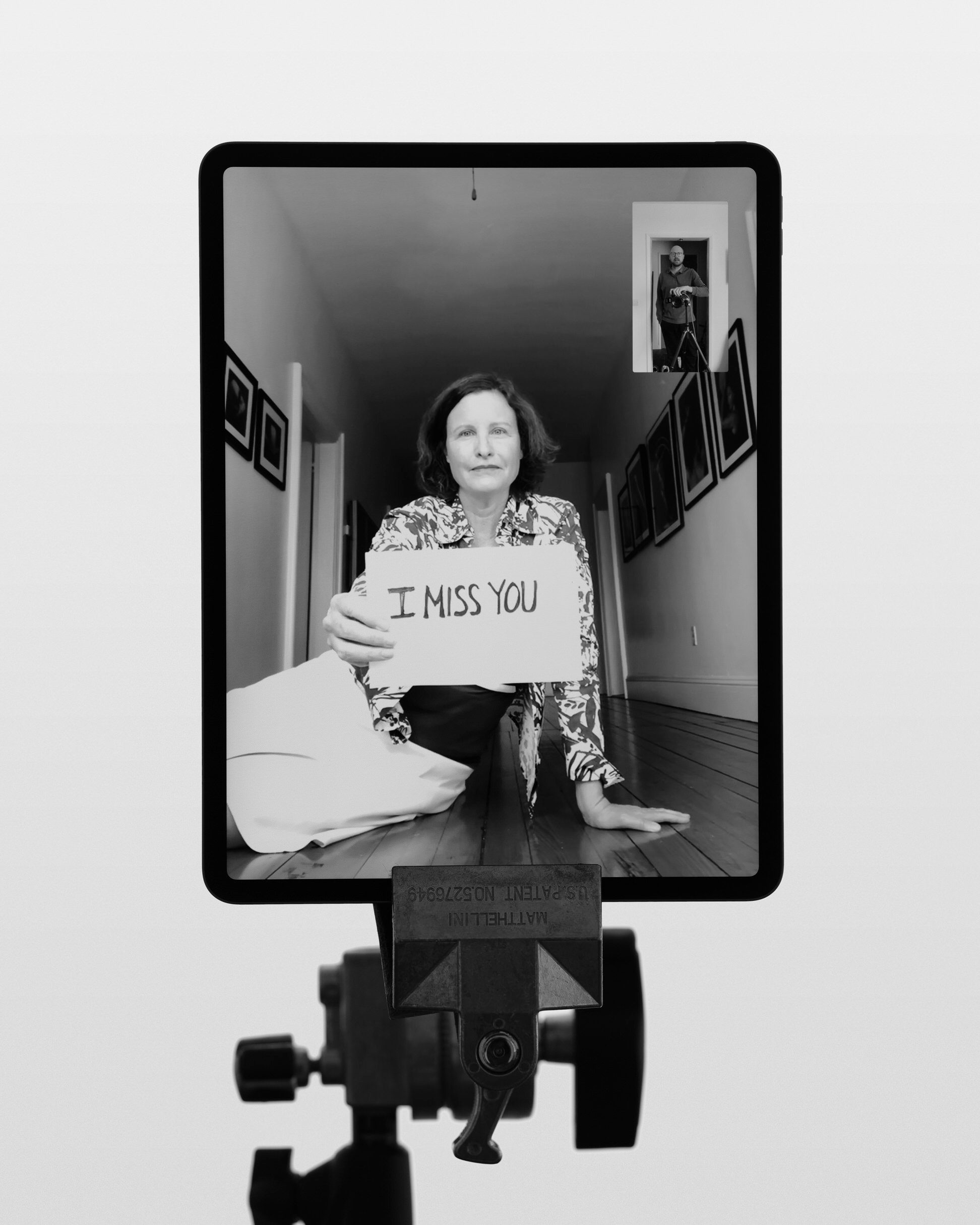 James Hole photographs woman with an I miss you sign in black and white Remote Personal