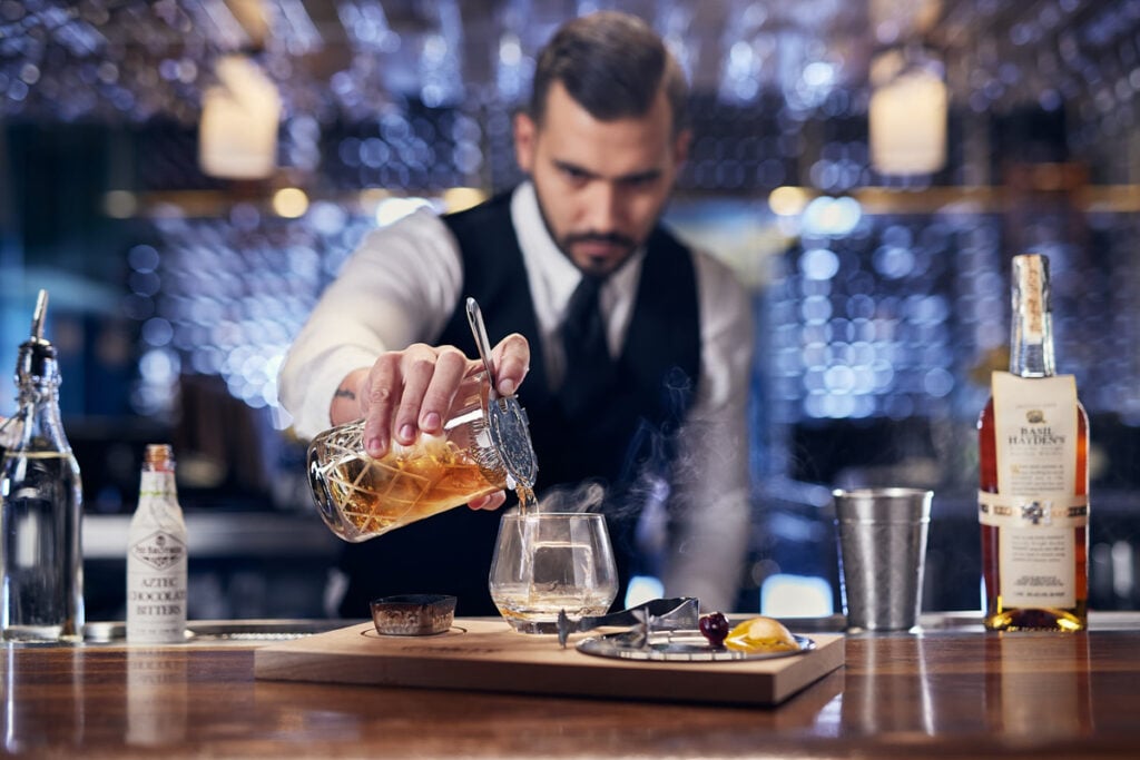 A bartender pours smoked whiskey into a glass by Mike Gluckman, Maitland, Florida