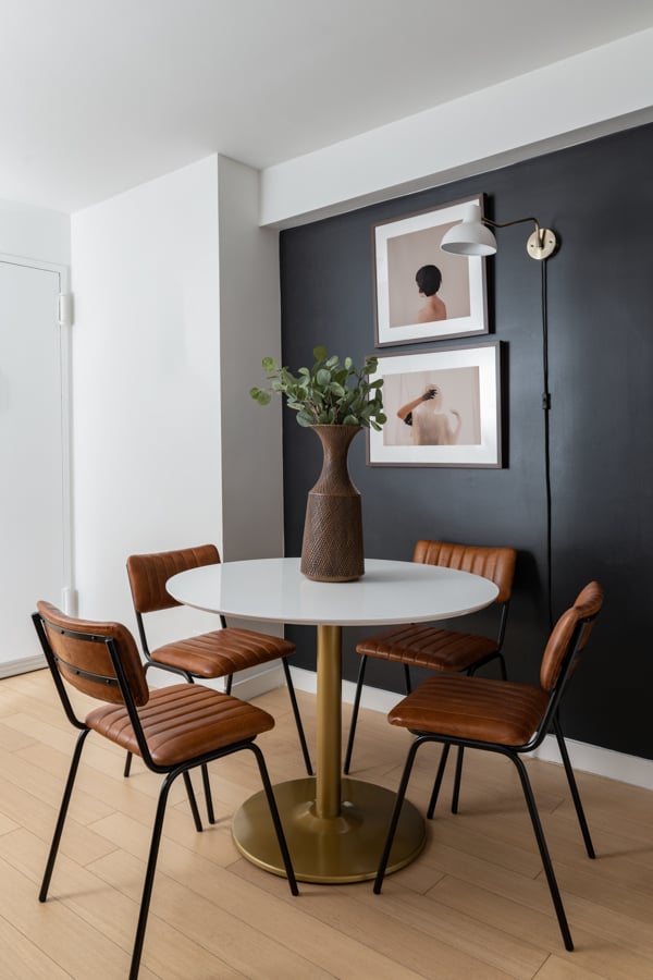 Interior shot by Morgan Ione of a small dining table adorned by a plant and in front of art.