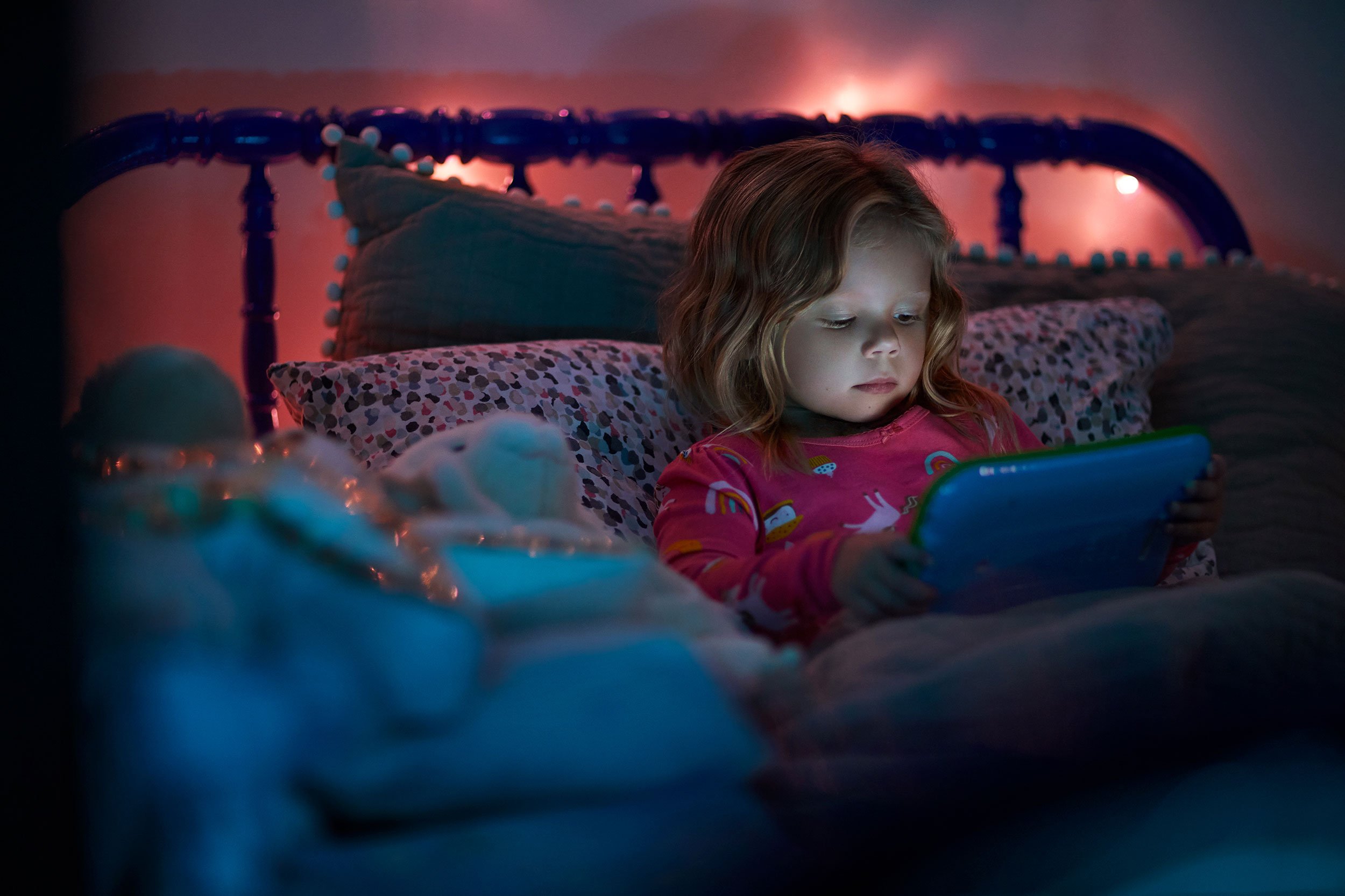 Natalia Weedy Calix a young White child in bed at night using a device rather than sleeping