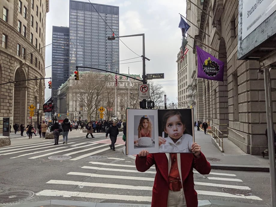 a person holds a portfolio open in front of their face in the street of new york