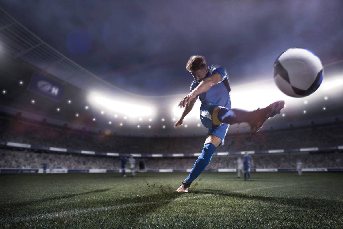 Photo of a player kicking a soccer ball into the air.