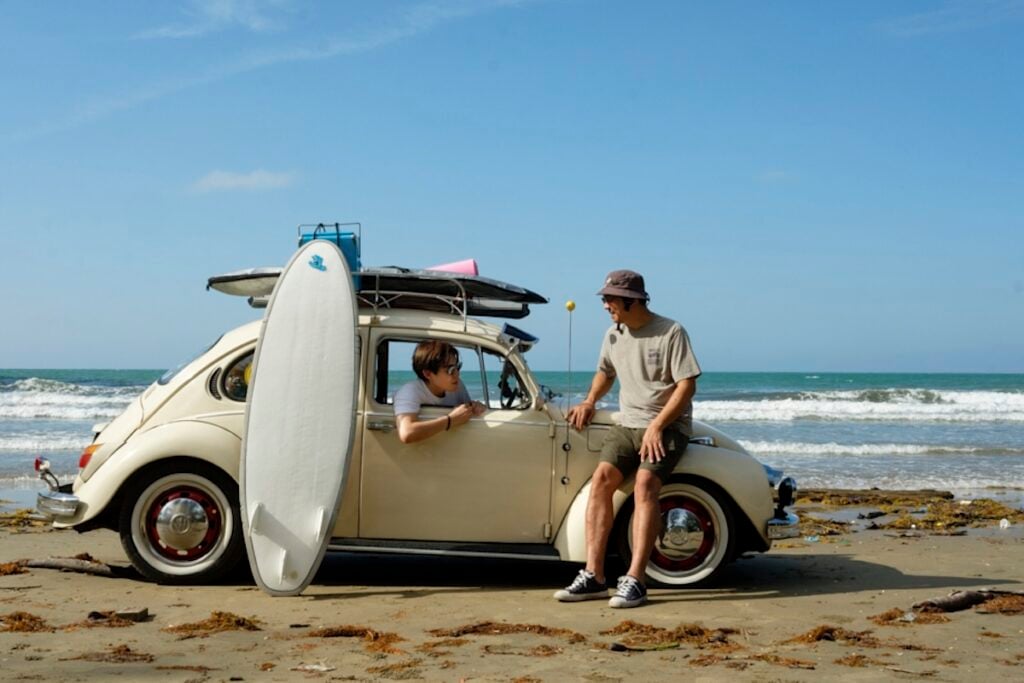 A photo of two men with a VW Beetle and their surfboards on the beach, shot by Alvin Ng.