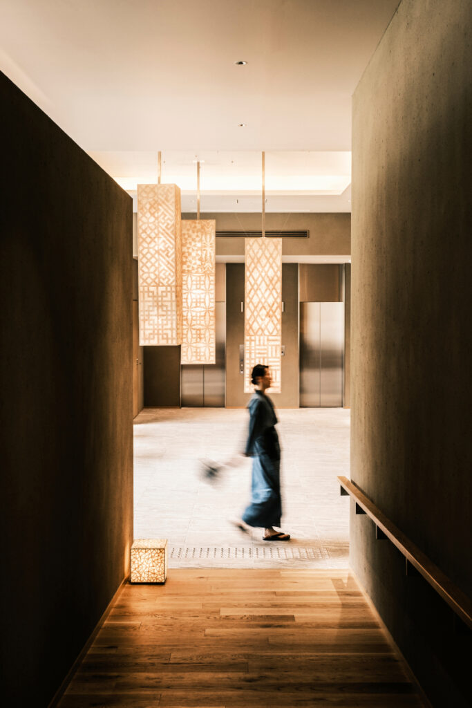 The image captures the essence of a modern interior bathed in abundant light, with the blurred figure of a woman gracefully moving through the halls, adding a touch of mystery and dynamism to the scene.