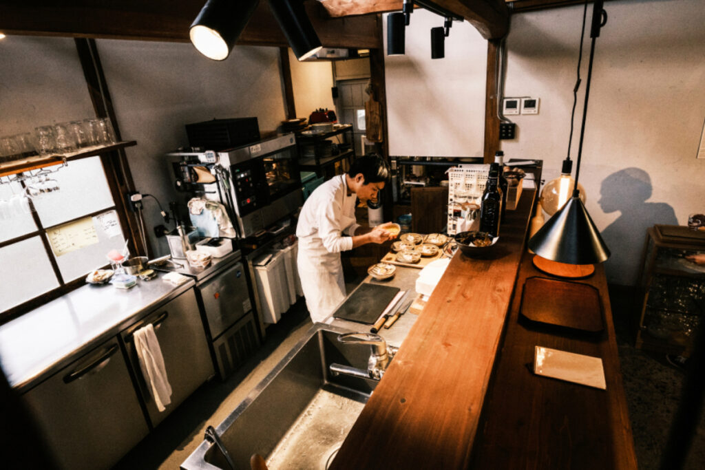 A photograph captures the artistry of a skilled chef meticulously preparing food in a restaurant kitchen, showcasing dedication, precision, and the culinary magic that unfolds behind the scenes.