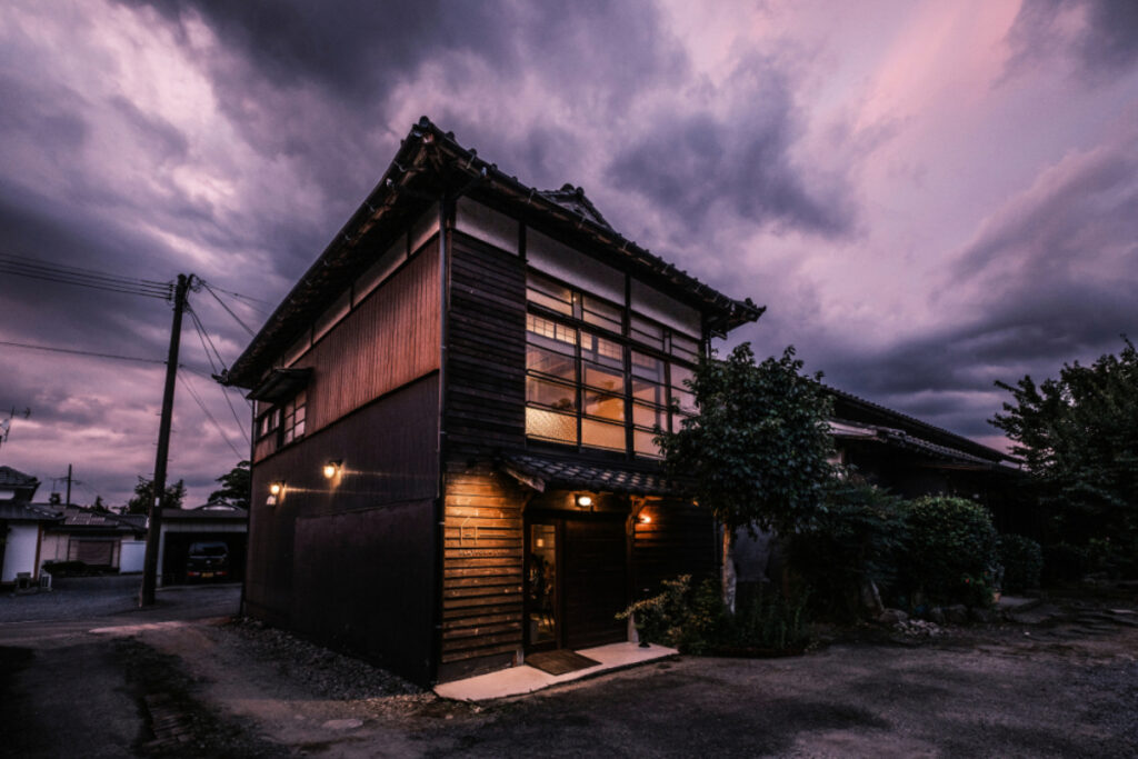 A captivating scene capturing Japanese architecture bathed in the soft, melancholic glow of twilight, as the sky sets the backdrop in hues of dusky blues and subtle, fading light.