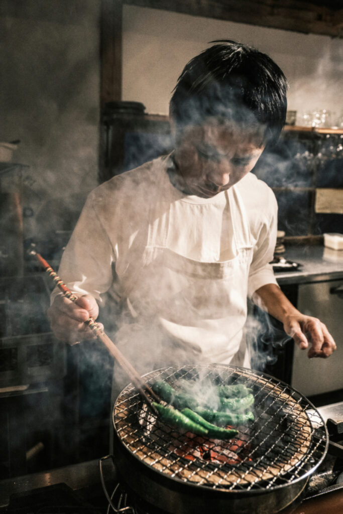 A man expertly preparing a meal on a sizzling grill, enveloped in swirling steam and aromatic smoke, adding a captivating ambiance as he tends to the culinary masterpiece.
