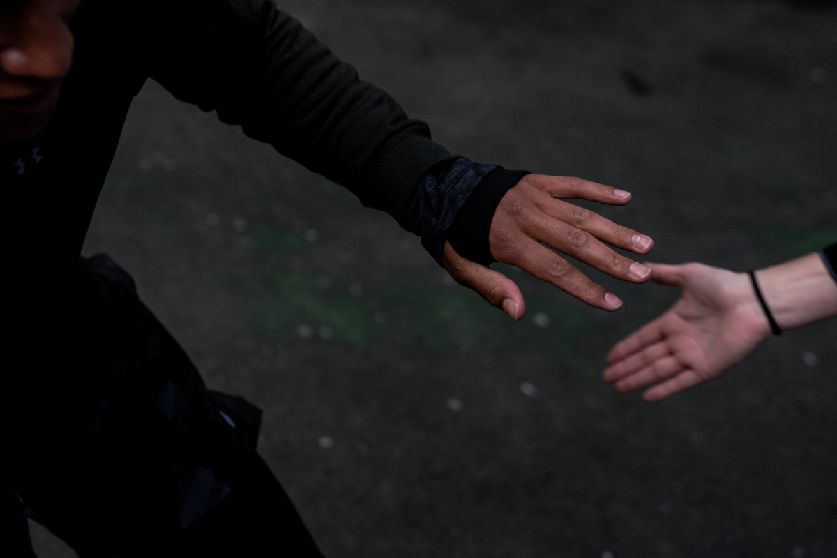 A color photograph by Brendan Davis of the hands of two people reaching for one another during an exercise routine.