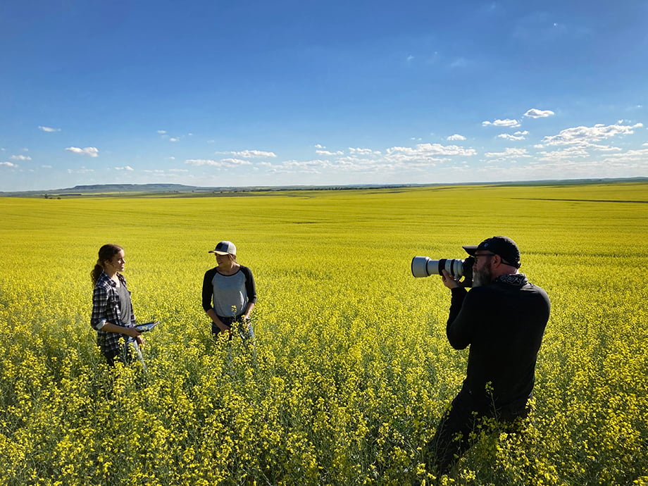 BTS - Greg photographing two members of the farm family inspecting the canola crop. 