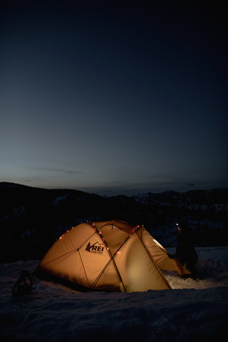 A color photograph by Carina Anne Swain Skorbecki of an illuminated tent in a snowy dusk landscape.