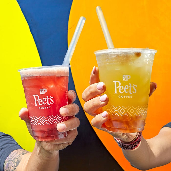 Two people holding Peet's iced drinks in front of colorful background.