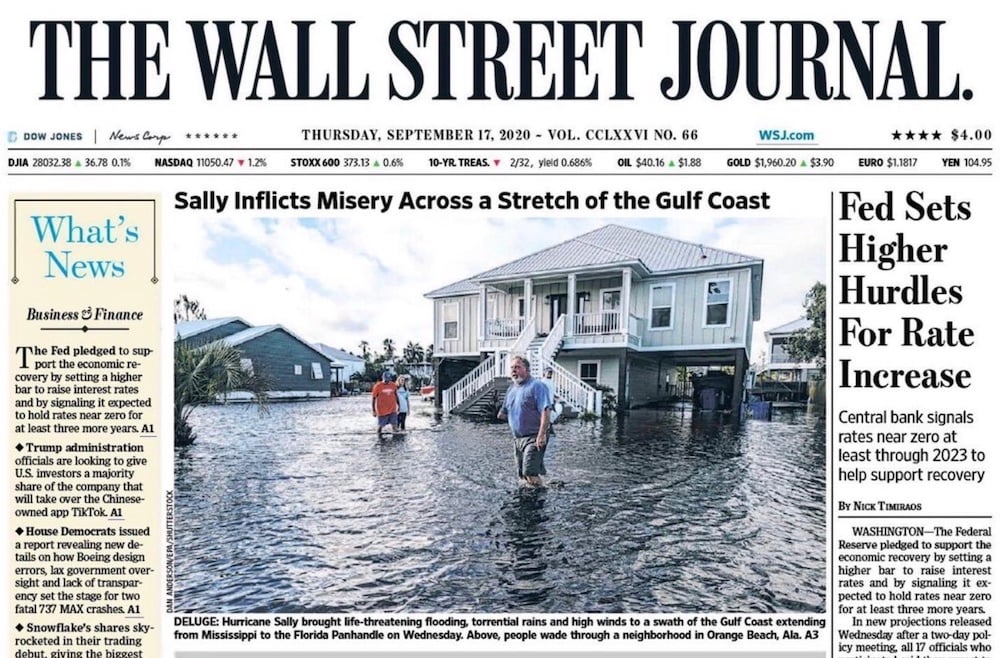 Tear sheet of figures standing in flood waters outside of stilted house, by Mobile-based breaking news photographer Dan Anderson.