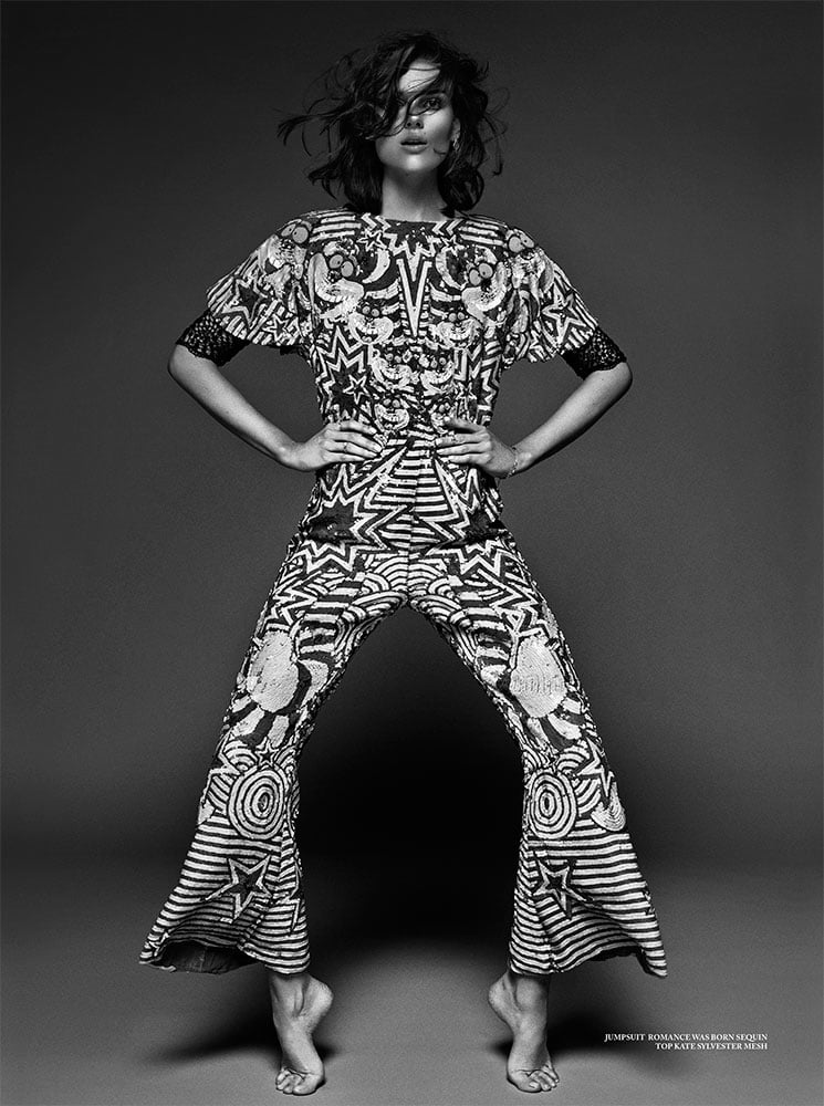 A photo by Emily Abay of a woman standing on tip-toes wearing a intricately patterned outfit.