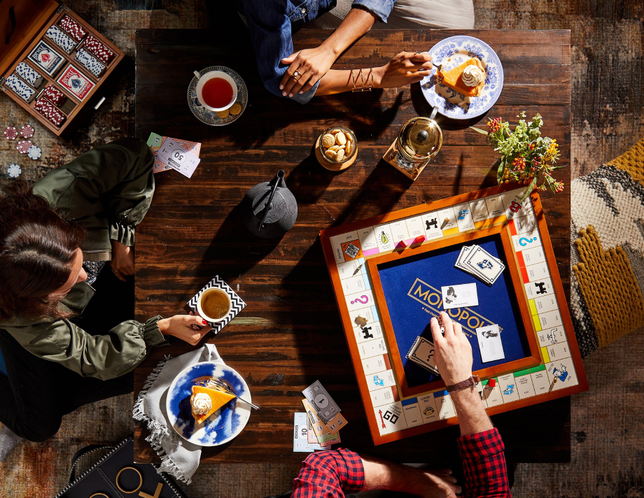 Aerial view photo of friends playing Monopoly while drink tea and eating cake, taken by NYC-based lifestyle photographer Evi Abeler. 