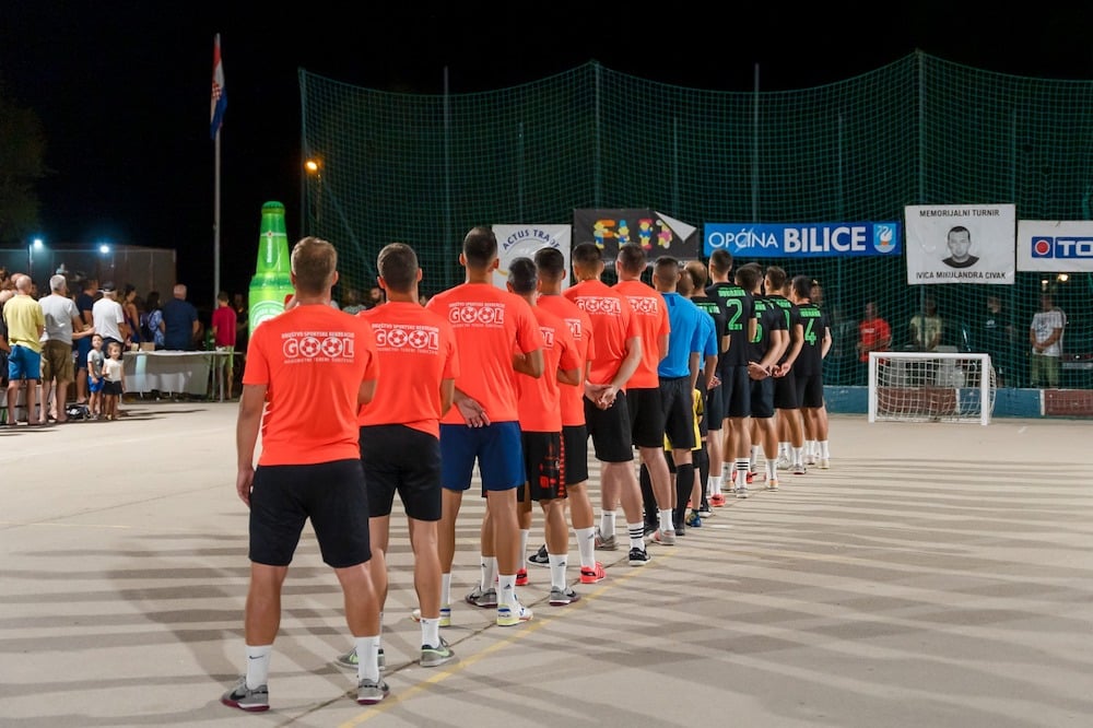 Image of two teams and referees standing in line formation at the championship game, for the singing of the Croatian national anthem.