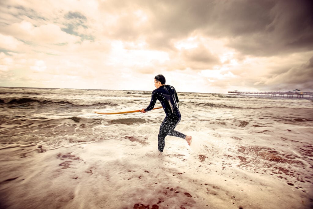 A surfer runs into the ocean with his board by photographer George Kamper of Miami, Florida 