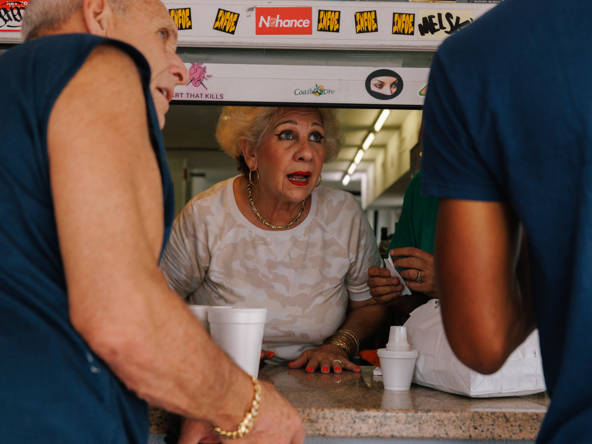 A color photo by James Jackman of Lucy Pla taking orders from the window of Enriqueta's Sandwich Shop.