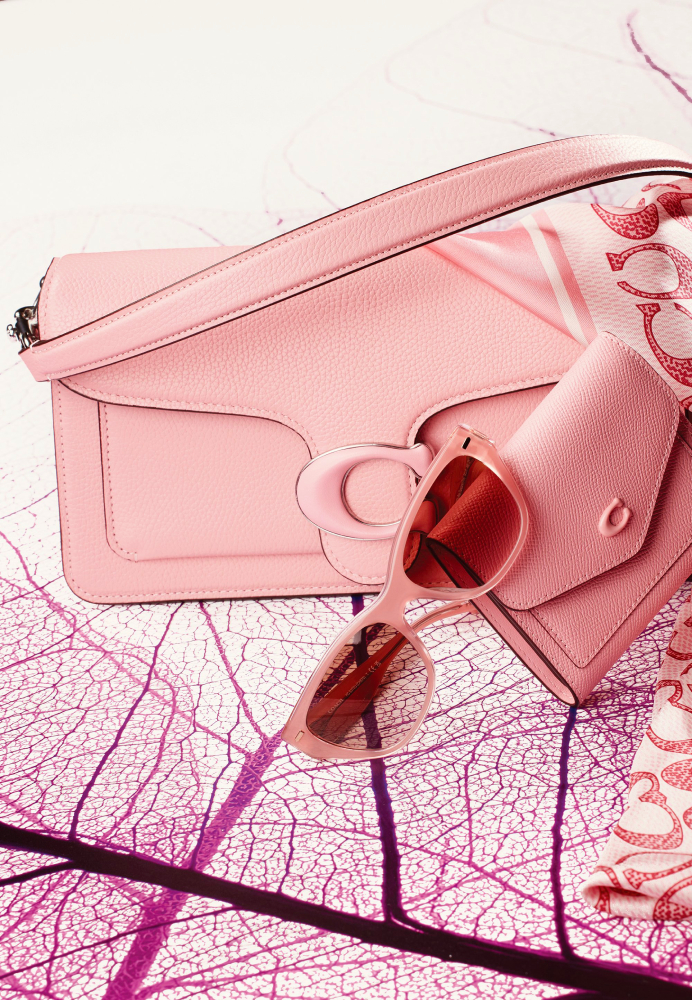 A color photograph by Jeff Englestad of a pink handbag, wallet, and sunglasses against a white and pink background.