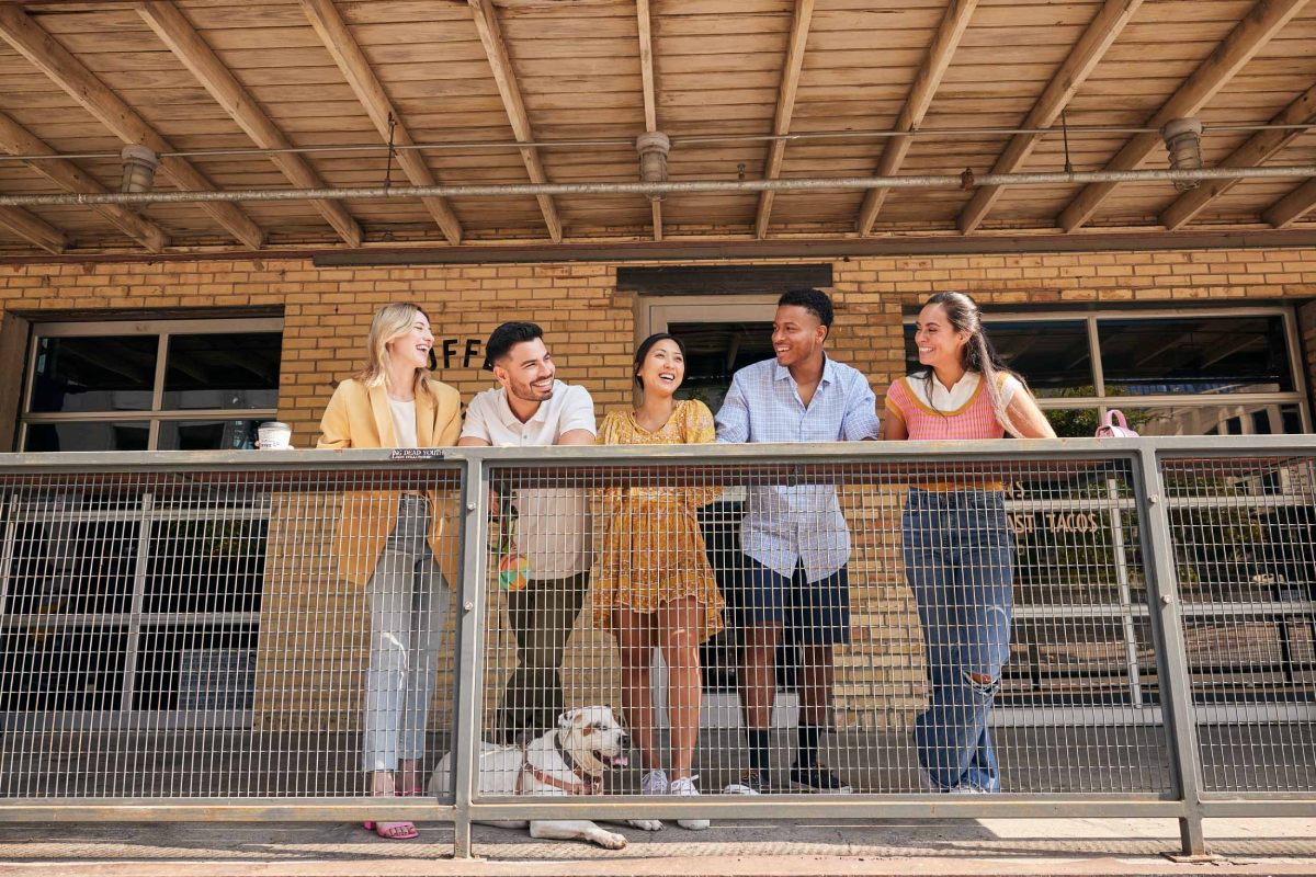 A color photograph by Jessica Attie, a lifestyle photographer in Austin, of a group of friends standing outside of a coffee shop. 