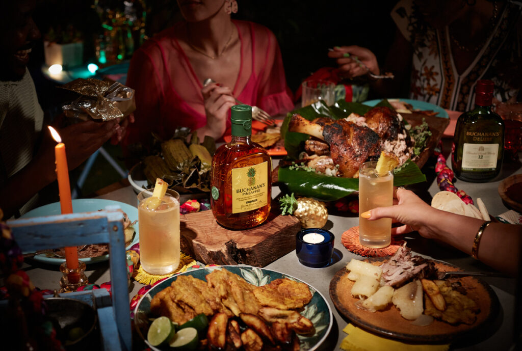 Two bottles of Buchanan's Whisky take their places on a beautifully set dinner table, where a sumptuous roast awaits, promising a perfect pairing of fine spirits and hearty fare.
