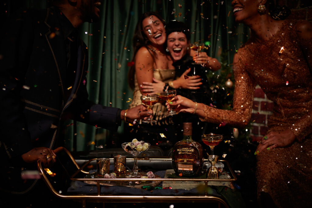 Amidst a flurry of confetti, joyous revelers raise their glasses of Buchanan's Whisky in celebration, photo by Jody Horton.