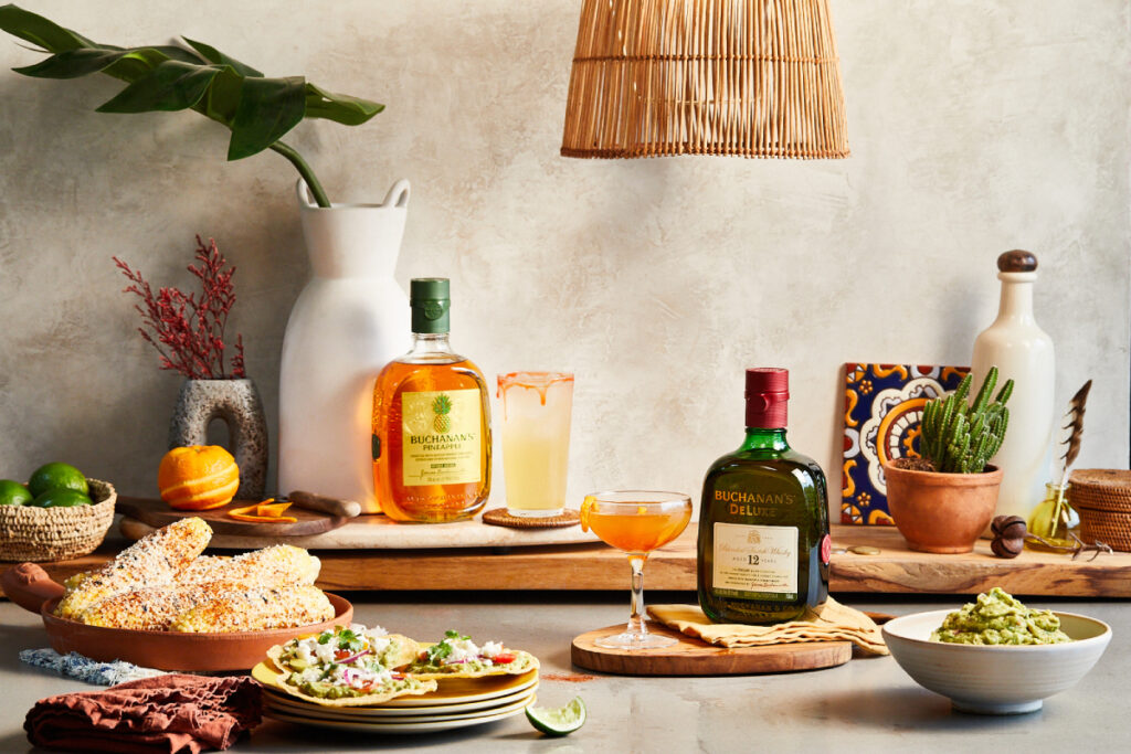 Buchanan's Whiskey takes center stage on a table adorned with vibrant corn, zesty guacamole, and tantalizing tacos, creating an inviting tableau that promises a delightful culinary experience paired with the smooth sophistication of fine whisky.